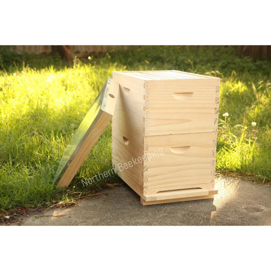 Wooden beehive on a grassy area with 'Northern Beekeeping' branding.
