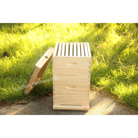 Wooden beehive on a grassy path with 'Northern Beekeeping' branding.