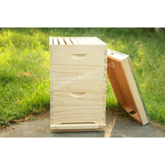 Wooden bee hive with open lid on a grassy background